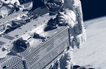 Un astronauta realiza trabajos fuera de la nave, con el planeta tierra al fondo.